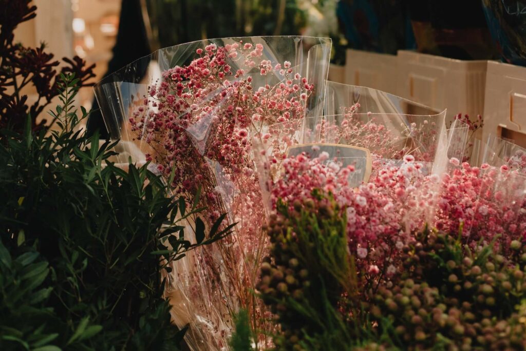 A man sells flowers from his tent at a market.
